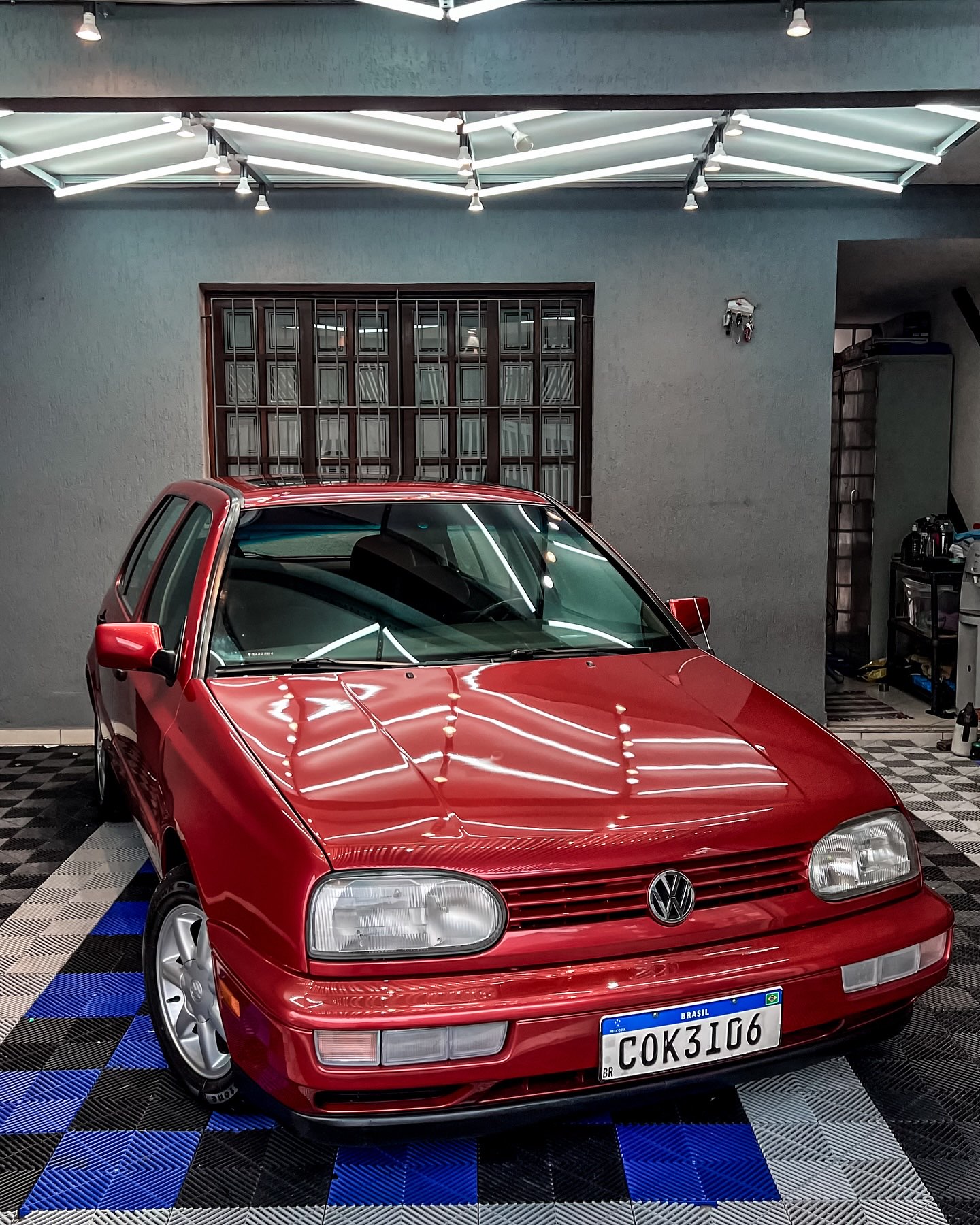 Golf vermelho fotografado no espaço da WRX Detail, com reflexos na pintura